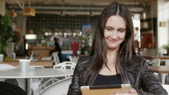 Stylish Young Woman Uses a Tablet and Sends Sms