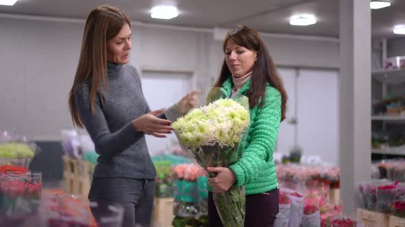 Positive Florist Bringing Bouquet of White and Green Flowers for Satisfied Buyer in Flower Shop