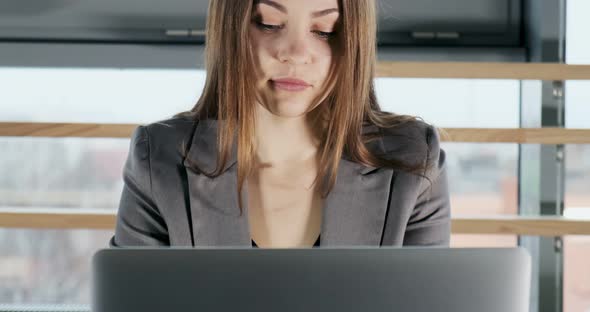 Concerned Woman Working on Laptop Computer and Looking Away Thinking Solving Problem at Office