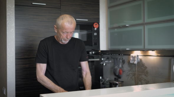 The Man At The Age Of Preparing a Meal In Their Modern Kitchen.