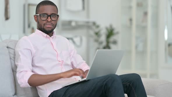 Thumbs Down By African Man with Laptop at Home