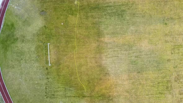 Top Down Aerial View of Football Field Surface Covered with Green Grass and Sprinklers Spraying