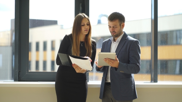 Businesswoman And Businessman Standing In Office And Discussing Business Ideas