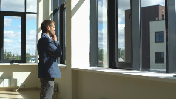 a Successful Businessman Looks Out The Window And Ponders The Business Plan