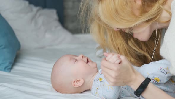 mom tickles baby lying in bed