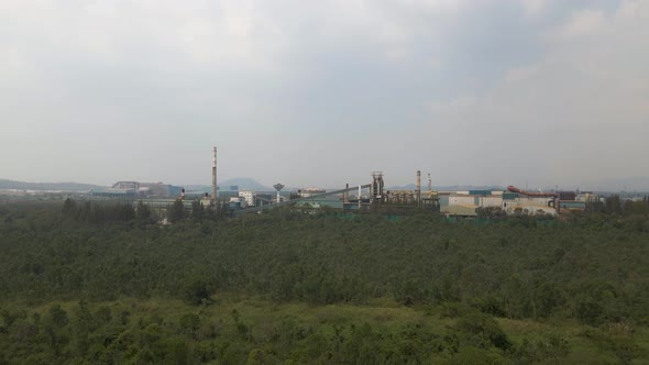 Aerial upwards revealing Powerplant station in distance surrounded by nature, Cloudy day