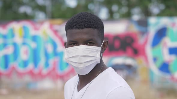 pandemic 2020 - serious black man with the mask stares at camera - background