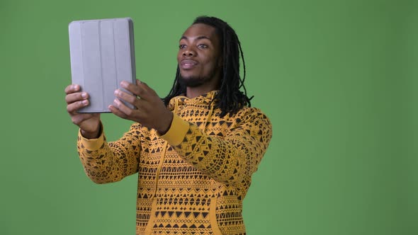 Young Handsome African Man with Dreadlocks Against Green Background