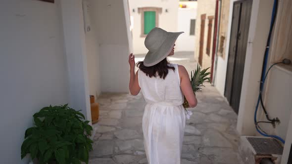 Back View Young Slim Woman in White Dress Walking on Town Street in Slow Motion Holding Healthful