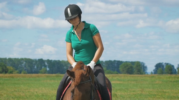A Young Beautiful Woman Riding a Horse At a Field