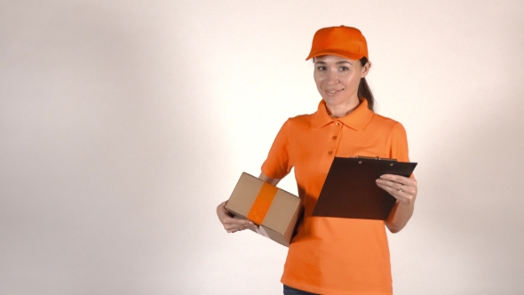 Beautiful Female Courier in Orange Uniform Delivering a Parcel. Light Gray Backround,  Studio Shot