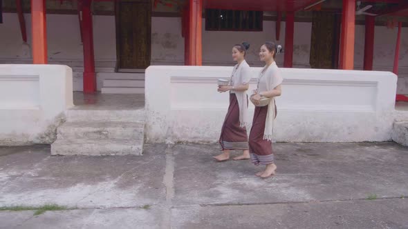 Two Girls In Thai Traditional Dress Walking Near Temple