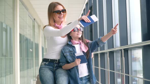 Mom and Daughter Holding Passports and Airline Boarding Pass Tickets