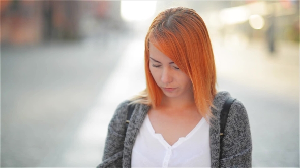 The Young Red-haired Female Tourist Attentively Considers The Map. The Girl Walks Streets Of The Old