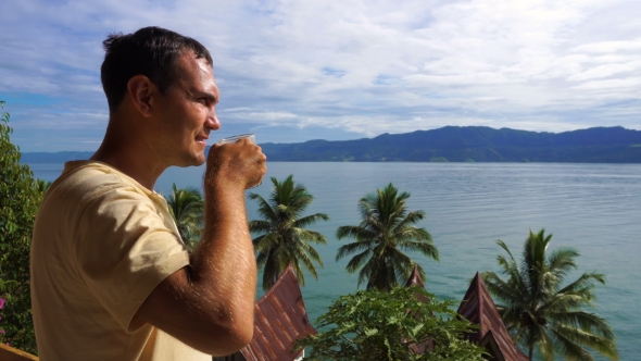 Male Traveler Drinking Coffee and Looking at Toba Lake From Samosir Island
