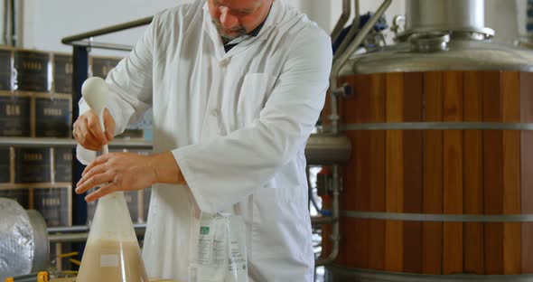 Male worker stirring liquor in flask 4k