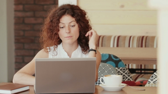 Woman In a Cafe , Drinking Coffee And Working On The Laptop .