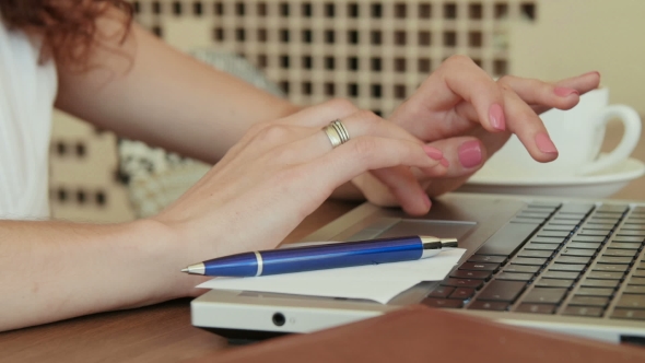 Woman In a Cafe , Drinking Coffee And Working On The Laptop .