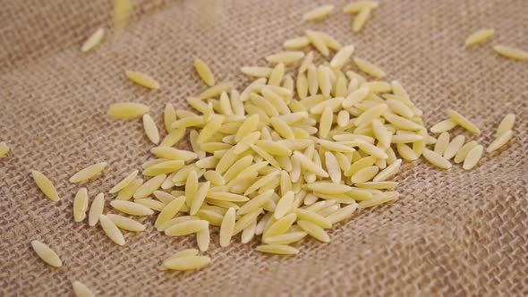 Dry peeled barley falling on a rough burlap. Macro. Slow motion