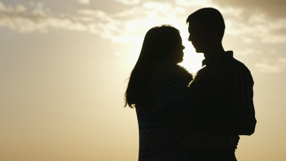 Silhouettes Of Young Men And Women Against The Sky. Couple In Love
