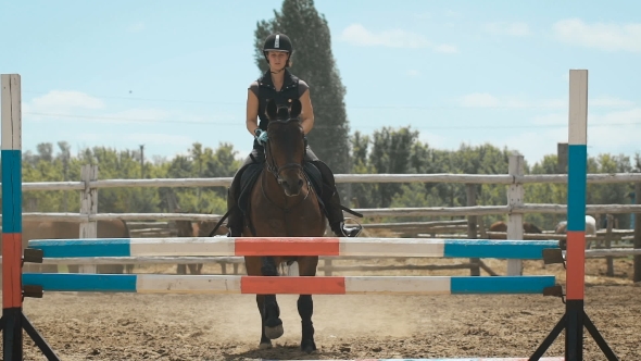 Young Woman Jumps Horse Over An Obstacle During Her Training In An Arena