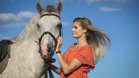 A Beautiful Charming Blonde Woman Walking With a Horse At a Field