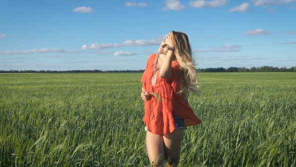 Beautiful Young Blond Woman With the Sexy Look Standing and Enjoying Herself at a Green Field