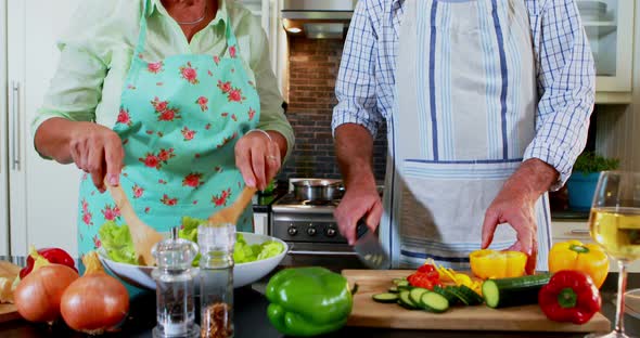 Senior couple preparing salad in kitchen 4k