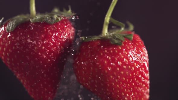 Two Big Strawberries are Flying and Colliding on a Black Background