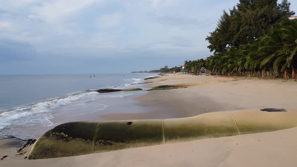 Aerial, low flyover tropical beach with giant aqua bags on shore to prevent erosion caused by rising