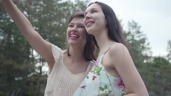 Portrait Two Pretty Smilling Happy Young Women Wear Summer Dresses Standing in the Top of Rock