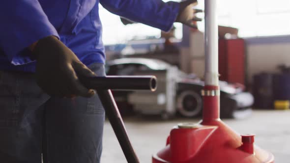 Female mechanic placing oil changing equipment under the car at a car service station