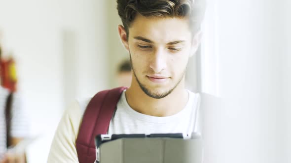 Teenage boy using a digital tablet in college corridor