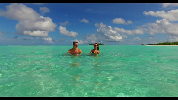 Teenage lovers sunbathing on tranquil resort beach vacation by blue ocean and white sandy background