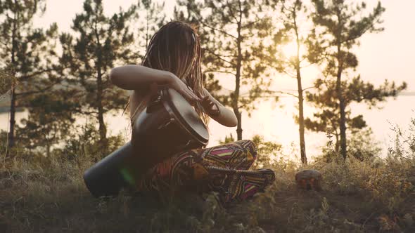 Beautiful Young Hippie Woman with Dreadlocks Playing on Djembe