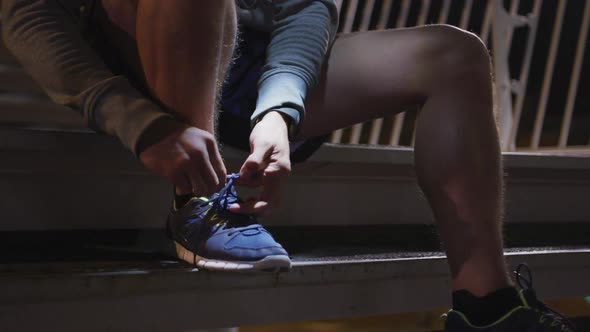 Caucasian male wearing a headlamp and tying his lacet on stairs in the evening