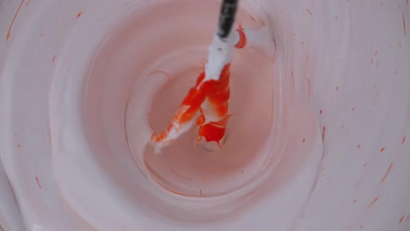 Mixing White with Red Paint in the Bucket Using Whisk on a Drill. Slow Motion