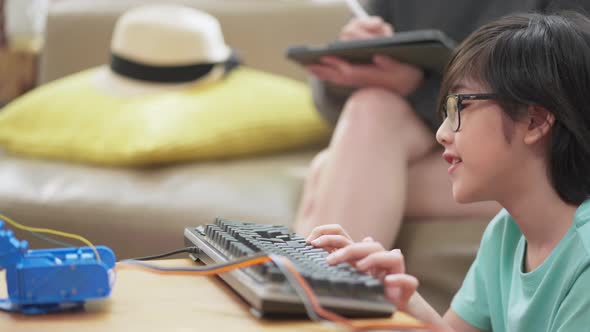 asian boy child with father mom control robot arm on Digital tablet and computer keyboard