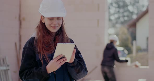 Smiling Young Female Architect Using Digital Tablet at Site