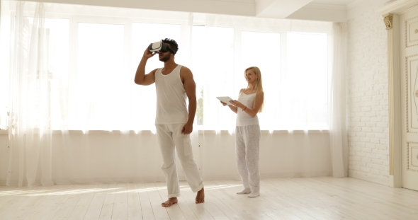 Man Using a Virtual Reality Glasses and the Woman is Holding a Digital Tablet 