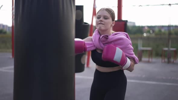 Motivated Plussize Woman Hitting Punching Bag in Slow Motion Outdoors Training