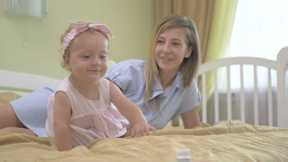 The Little Girl Climbs On Her Knees On The Bed