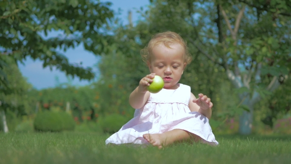 Baby Putting Green Apple On The Grass.
