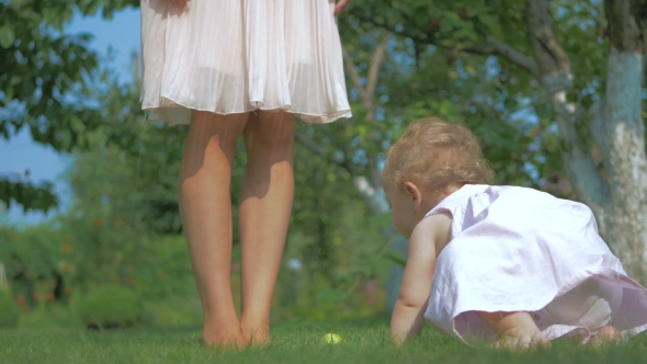 Baby Crawls To The Mother's Foot On The Grass.