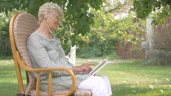 Elderly Woman Switches The Music On The Tablet.