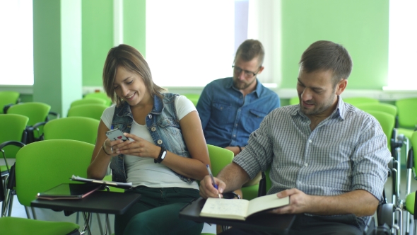 Smiling Young Male Student With Others Writing Notes in the Classroom