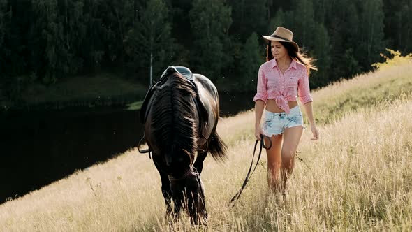 Beautiful Woman in Hat Leads a Horse. Young Girl Spending Outdoor Leisure Activity, Enjoying