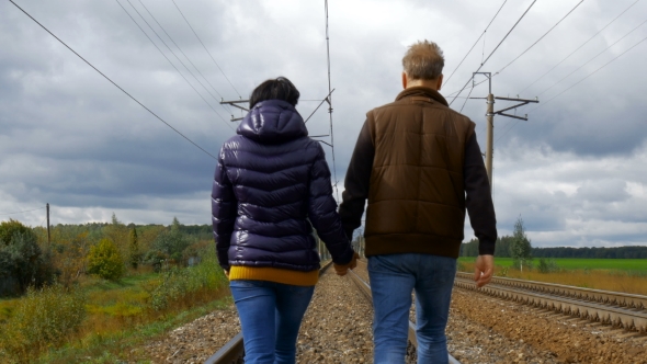 Couple Walking On Railroad Tracks