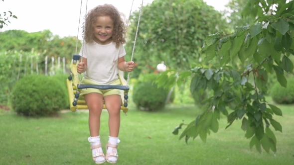 Little Girl Riding On a Swing In The Park