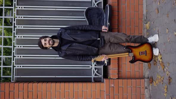 Happy Guy Smiling on the Street with a Guitar